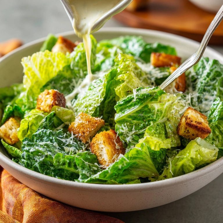 Caesar Salat mit Croutons und Parmesan wird mit Dressing übergossen, Nahaufnahme der Zubereitung.