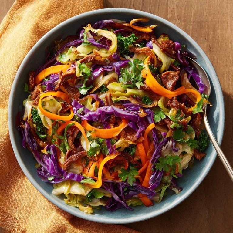 Knackiger Rind-Kohl-Wok von oben in einer blauen Schüssel mit Karottenstreifen und Petersilie garniert