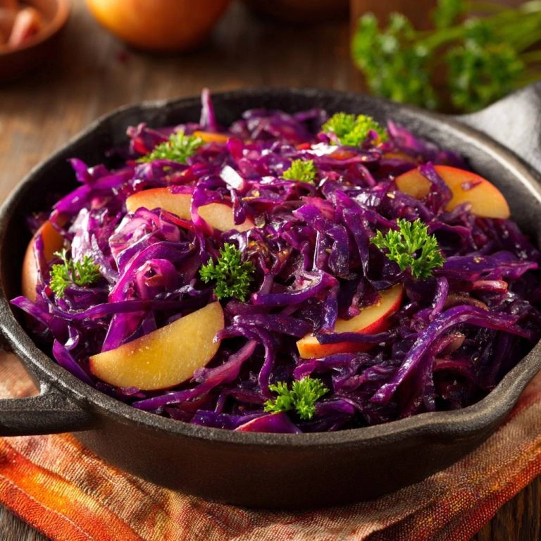 Saftiger Apfel-Rotkohl in gusseiserner Pfanne mit frischer Petersilie und Apfelstücken garniert