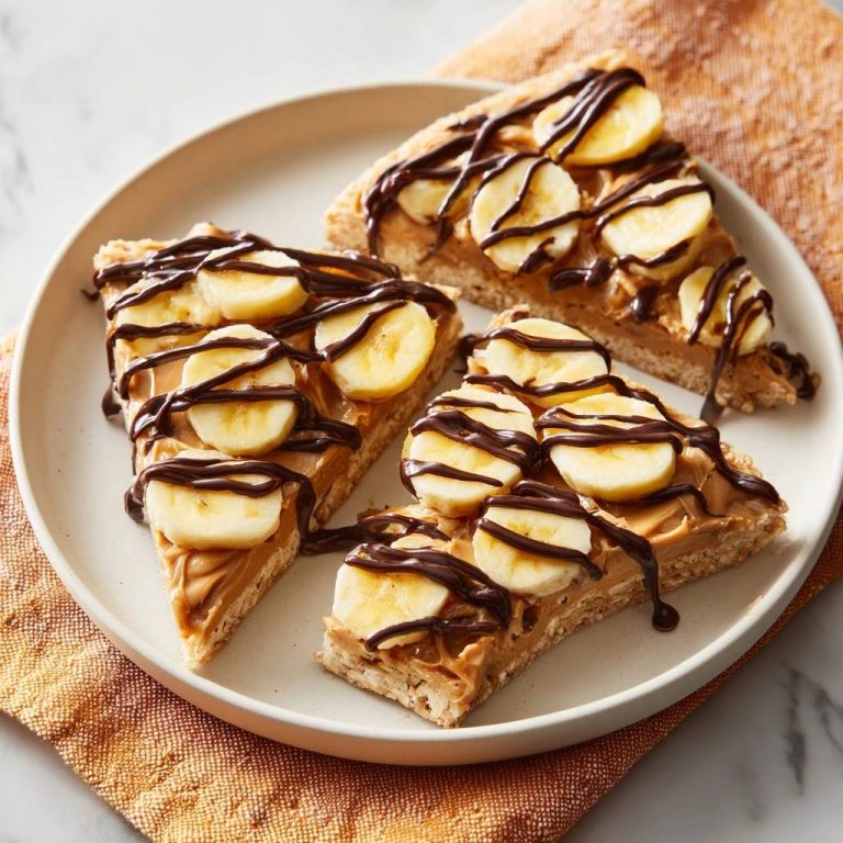 Knusprige Erdnussbutter-Bananen-Schoko-Pizza angeschnitten auf einem Teller serviert mit Schokoladensauce und Bananenscheiben.