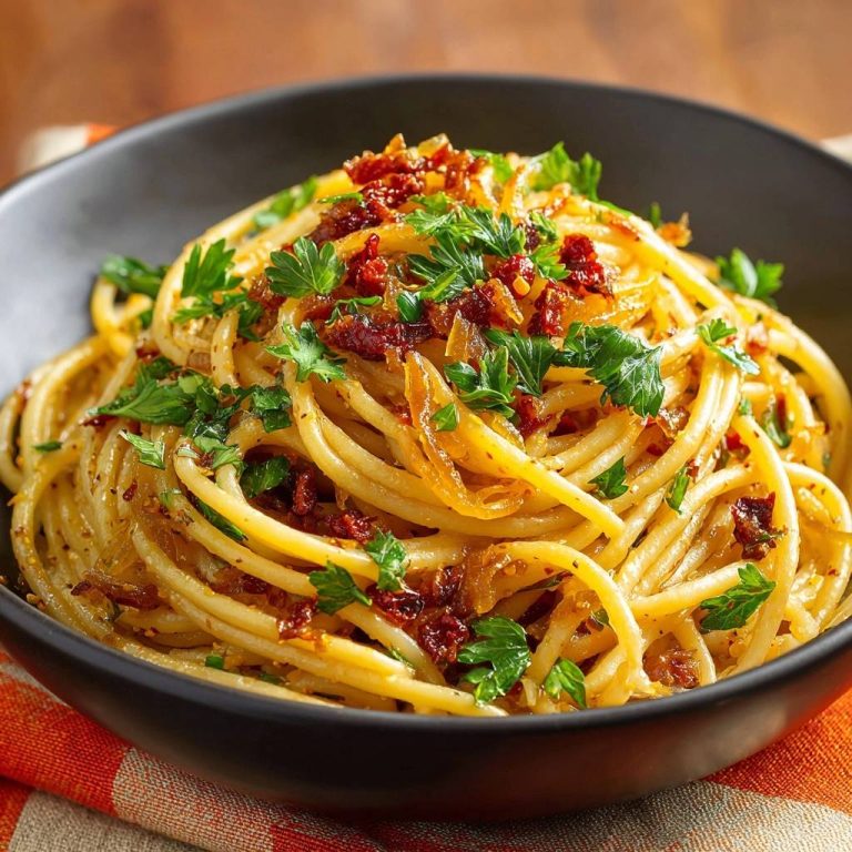 Knusprige Zwiebel-Spaghetti mit Tomaten als Nahaufnahme mit frischer Petersilie garniert in einer schwarzen Schüssel.