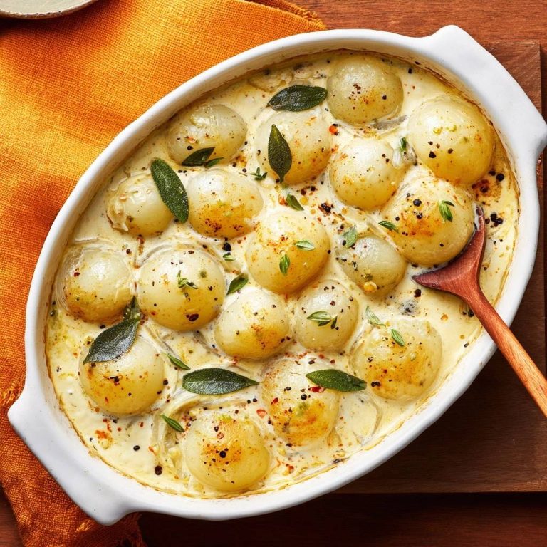 Cremige Perlzwiebeln mit Salbei, eine Draufsicht auf die Zwiebeln in cremiger Sauce mit Kräutern garniert.