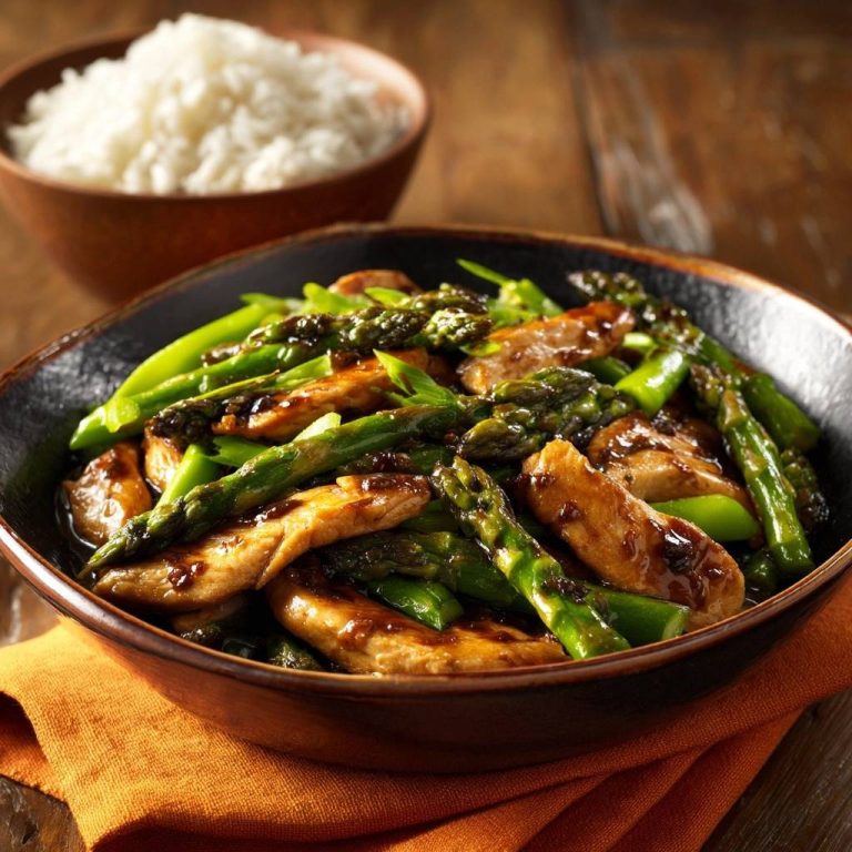 Hähnchen-Spargel-Pfanne à la Asia, eine Nahaufnahme der saftigen Hähnchenstreifen und knackigen Spargelspitzen in einer dunklen Sauce.