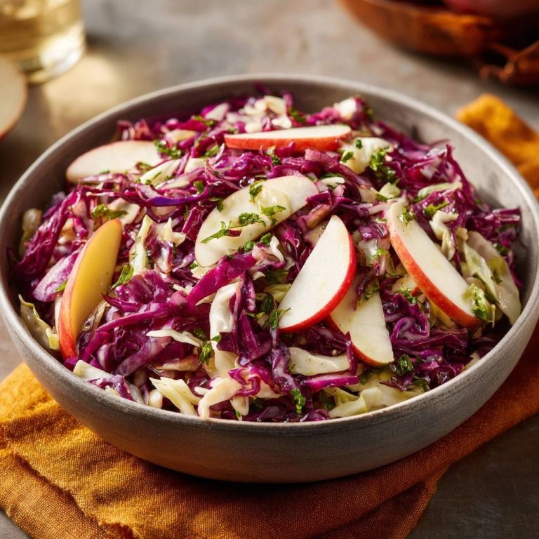 Knackiger Rotkohl-Apfel-Salat in einer Schüssel mit Apfelspalten und Kräutern, Nahaufnahme
