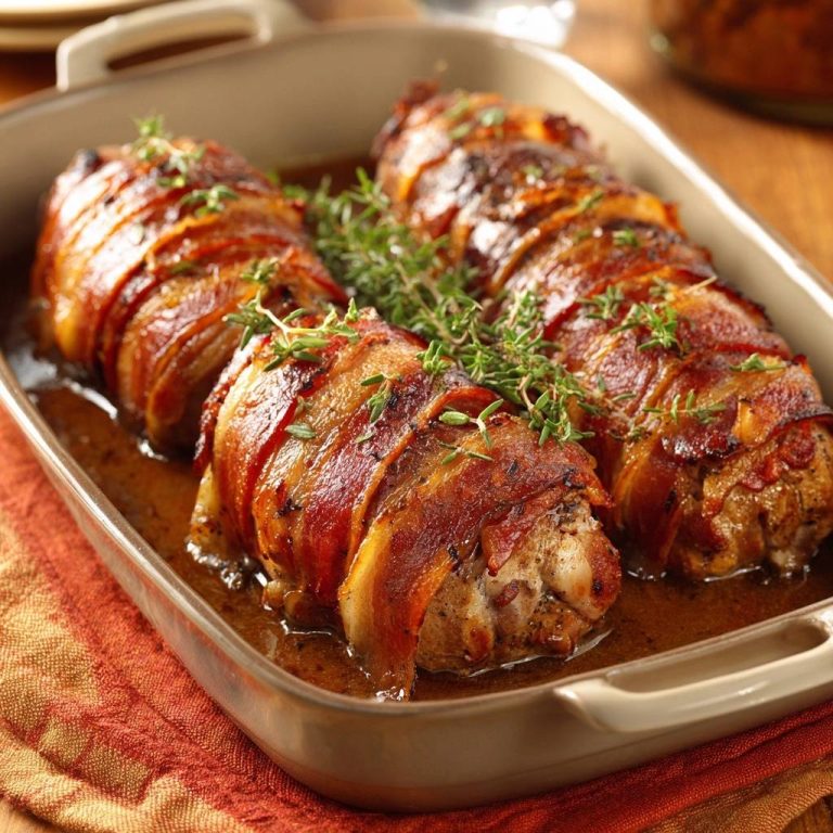 Speckumwickeltes Hähnchenfilet mit Thymiansauce in einer Auflaufform, saftig und goldbraun gebacken.