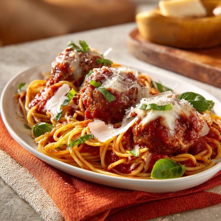 Italienische Spaghetti mit Fleischbällchen, detailnah mit Parmesanspänen und Basilikum garniert.