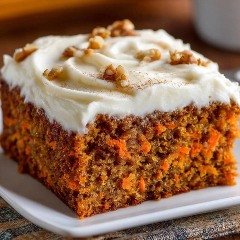 Saftiger Karottenkuchen mit Frischkäse-Frosting als angeschnittene Portion mit Walnüssen und Zimt bestreut.