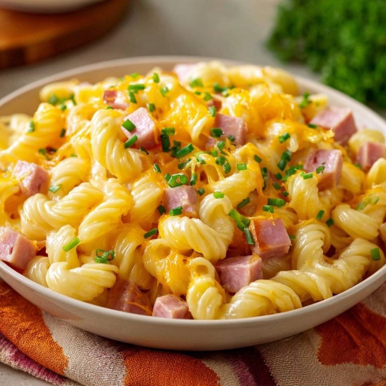 Cremiger Schinken-Fusilli-Auflauf als Nahaufnahme, garniert mit frischen Kräutern und geschmolzenem Käse.