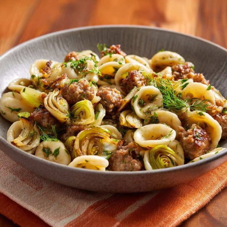 Orecchiette mit Salsiccia und geröstetem Fenchel, serviert in einer Schüssel mit frischen Kräutern garniert.